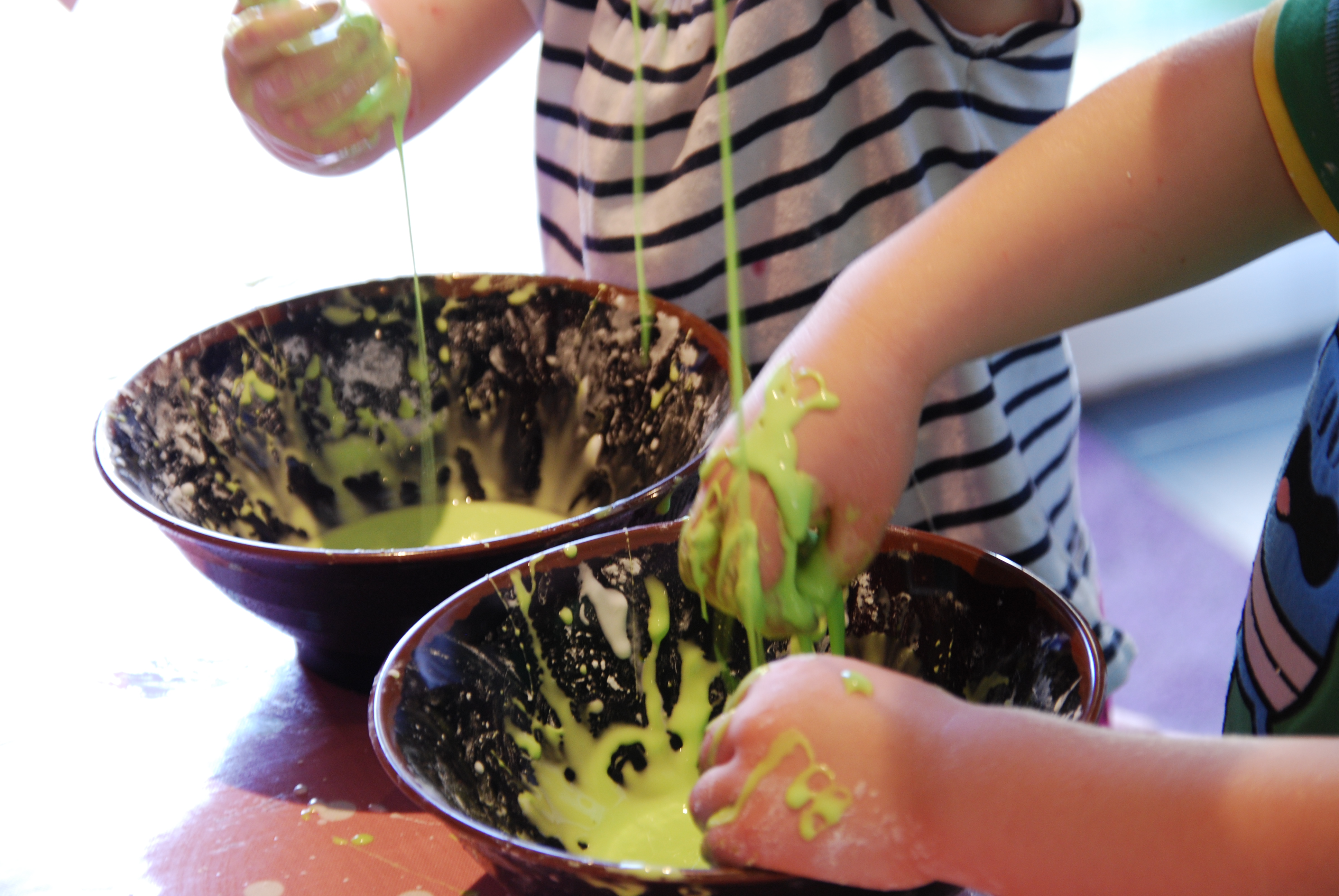 two children playing with bowls of oobleck